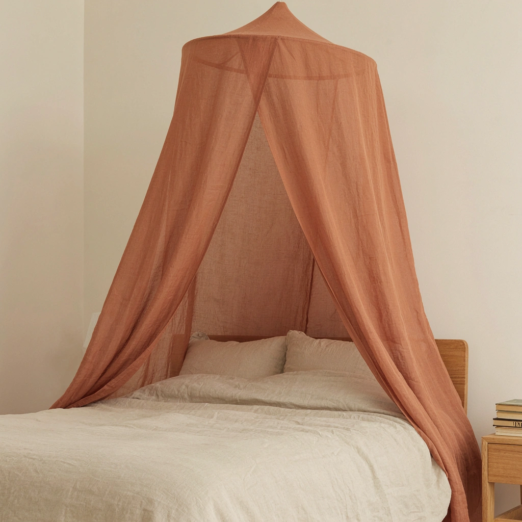 Ciel de lit en mousseline terracotta au-dessus d'un lit double